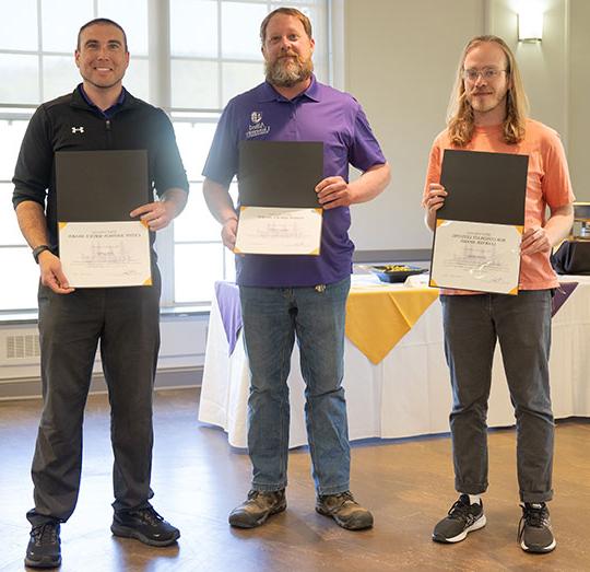 three men standing, holding certificates