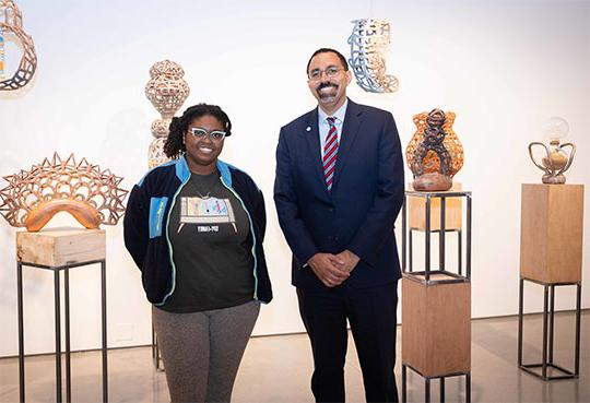 Man in shirt and tie with woman in front of art exhibit